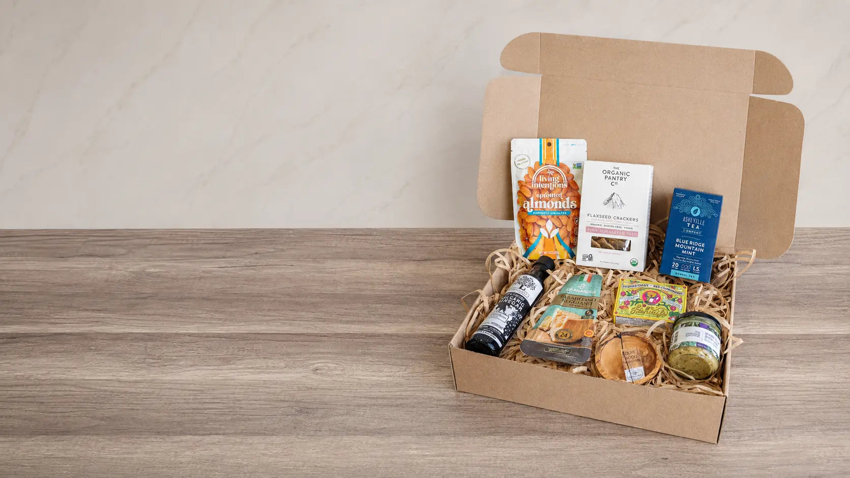 RaizBack curated gourmet gift box with roasted almonds, organic crackers, artisan tea, preserves, cookies, and specialty pantry foods.