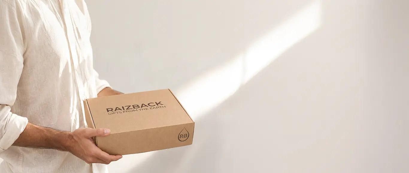 Person holding a RaizBack “Gifts from the Earth” gourmet gift box in a bright, minimalist setting.